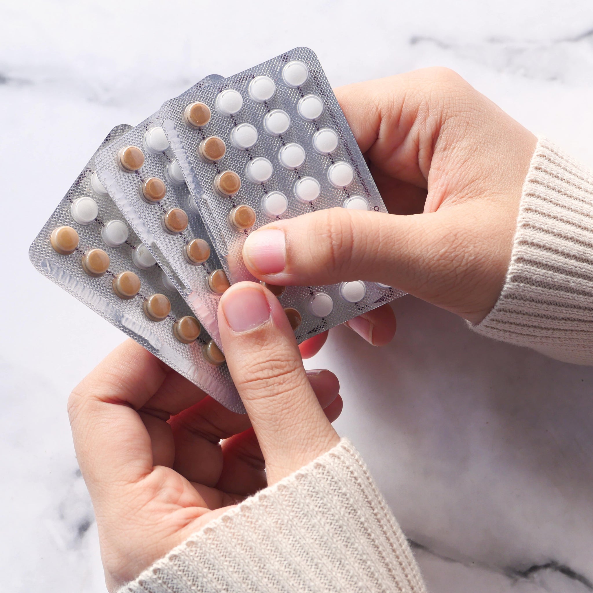 Frau hält drei Blister mit der Anti-Baby-Pille in der Hand
